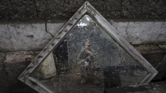 A Ukrainian serviceman is reflected in a mirror as he smokes a cigarette