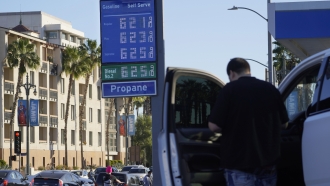 A motorist pauses at a gas station displaying higher gasoline prices at a Chevron station downtown Los Angeles