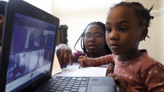 A 4-year-old participates in her virtual classes as her mother assists