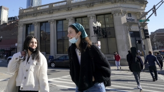 Passers-by wear masks under their chins