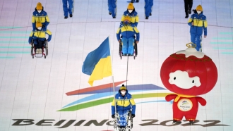Maksym Yarovyi of Ukraine carries the flag as the team makes their entrance during the Paralympics opening ceremony