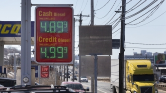 A sign at a gas station displays gas prices.
