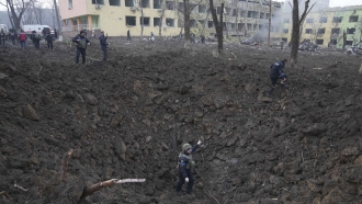 Ukrainian soldiers and emergency employees work at the side of the damaged by shelling maternity hospital in Mariupol