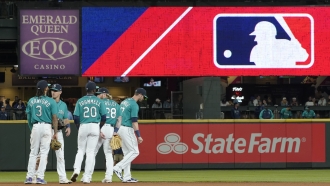 Seattle Mariners gather on the field with the MLB logo displayed above them