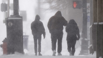 People walk among blowing snow