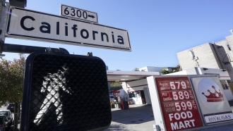 A California street sign is shown next to the price board at a gas station.