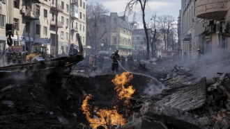 Firefighters extinguish flames outside an apartment house after a Russian rocket attack in Kharkiv.