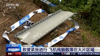 Debris is surrounded by police tape and marked at the site of a plane crash in China