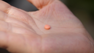 A woman holds an aspirin pill