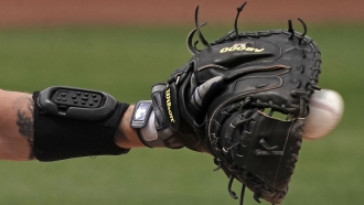 Seattle Mariners catcher Tom Murphy wears a wrist-mounted device used to call pitches as he catches a ball