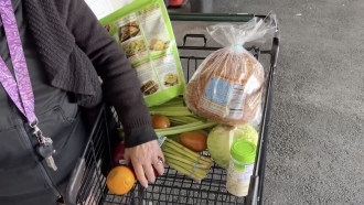 A woman at a food bank with groceries in a shopping cart