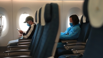 Passengers wearing face masks sit on a plane.