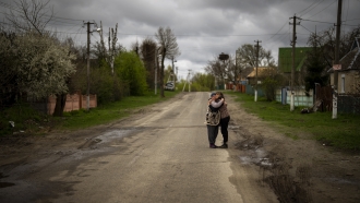 A woman hugs her neighbor during the funeral of her husband in Bucha, Ukraine