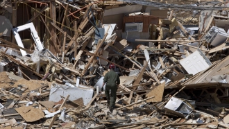 A man climbs a pile of rubble left from a natural disaster.