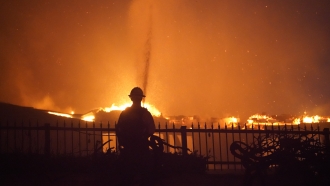 A firefighter works to put out a structure burning during a wildfire in California.