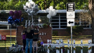 A family pays their respects next to crosses bearing the names of Tuesday's shooting victims at Robb Elementary School