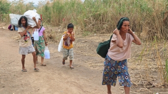 Displaced people in Myanmar carry donated lunch boxes