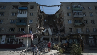 People clear out debris of an apartment building damaged by shelling in Mykolaivka, eastern Ukraine