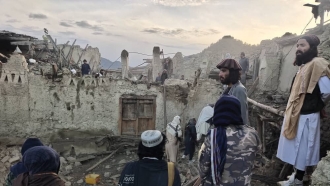 Afghans look at destruction caused by an earthquake.