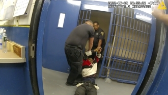 Richard Cox, center, is dragged into a cell after being pulled from the back of a police van after being detained