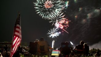 Spectators watch as fireworks explode overhead during the Fourth of July