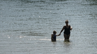 A woman and youngster wade in the waters of the American River at Discovery Park in Sacramento, California