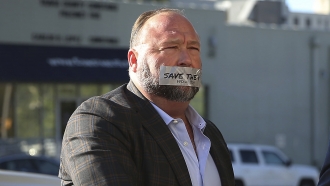 Alex Jones with tape over his mouth reading 