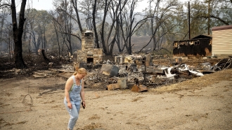 A woman passes a lodge that burned during the McKinney Fire.