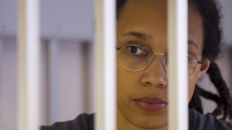 WNBA star Brittney Griner looks between bars of a detention cell.