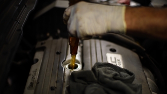 A mechanic refills oil in a car.