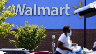 A shopper loads items into her car in the parking lot of a Walmart.