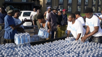 Apartment residents flock to a trailer full of water being delivered