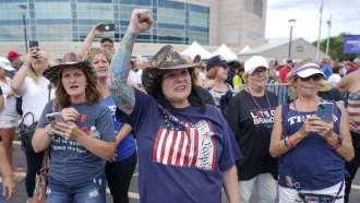 Supporters of former President Donald Trump cheer as they wait in line outside a political rally.
