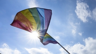 A rainbow Pride flag waves in the sky