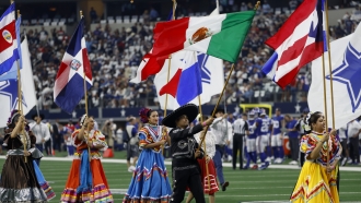 Participants carry flags from several different countries during a pregame ceremony celebrating hispanic heritage month