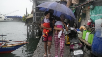 Residents carry their children as they evacuate to safer grounds to prepare for the coming of Typhoon Noru.