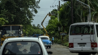 Operators from the electric company mounted on a crane try to repair broken power lines in the wake of Hurricane Ian.