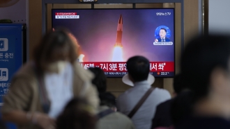 People watch a TV screen showing a news program reporting about North Korea's missile launch.