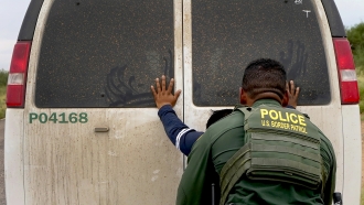 A migrant is searched by a U.S. Border Patrol agent.