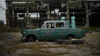 An abandoned car lies on the ground in a heavily damaged grain factory.