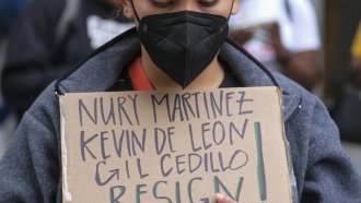 A protester holding a sign protest outside City Hall during a Los Angeles City Council meeting