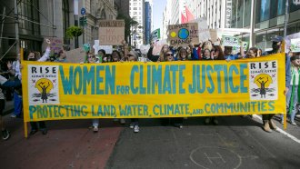Demonstrators hold a Women For Climate Justice banner