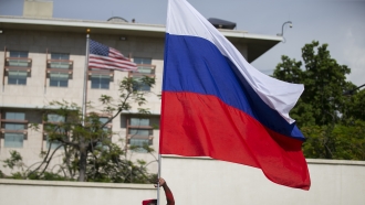 A man waves a Russian national flag in front of the U.S. embassy as he hopes for support from the Russian government