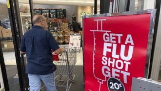 A shopper passes a sign urging people to get a flu shot outside a Hy-Vee grocery store in Sioux City
