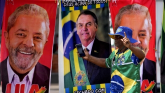 A person walks in front of flags for President Jair Bolsonaro and former President Luiz Inacio Lula da Silva.