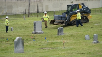 Workers bring equipment to the site where excavation takes place at Oaklawn Cemetery.