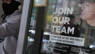 A hiring sign hangs in a window.