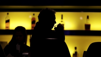 A patron sips his drink while having a meal at a bar