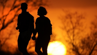 A couple walks through a park at sunset in Kansas City, Mo.