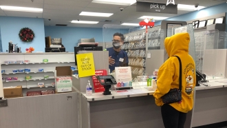 A person waits at a pharmacy counter.